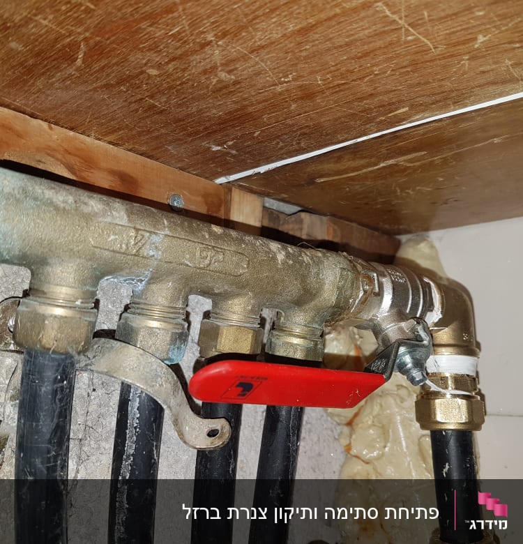צינורות מתכת עם ברז אדום מתחת לכיור